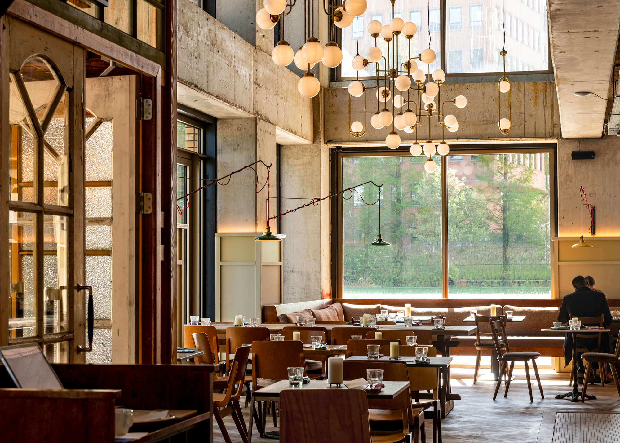 Café Pigalle's restaurant dining room with high ceilings, concrete pillars and a garden view